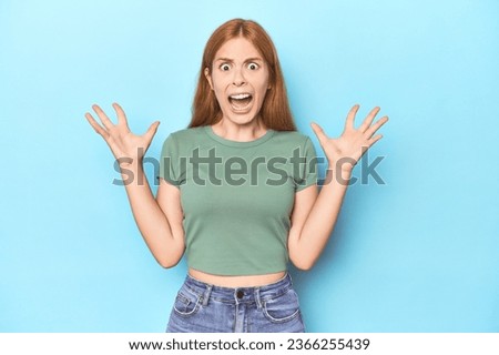 Redhead young woman on blue background screaming to the sky, looking up, frustrated. Royalty-Free Stock Photo #2366255439