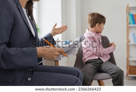 Child at psychologist's office. Kid refuses to talk, turns away and avoids eye contact. Resentful boy with communication and behaviour problems sitting on chair during therapy session with specialist Royalty-Free Stock Photo #2366266423