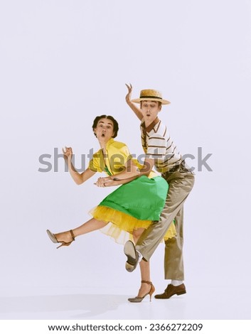 Joyful and talented young couple, man and woman in stylish clothes dancing isolated on white studio background. Concept of art, hobby, retro dance, vintage style, choreography, beauty. Ad