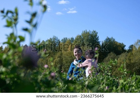Happy child and young mother, daughter hugs her mother in field. Daughter loving mother, hugging each other. Happy family having fun outdoors