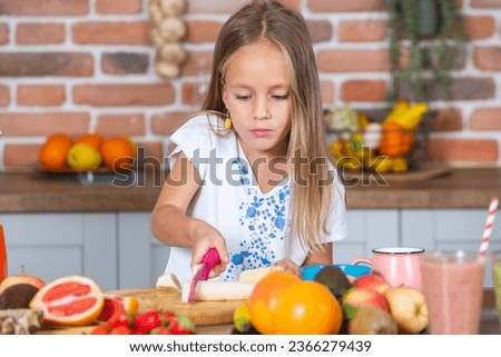 little girl eating healthy fruit salad in the kitchen at home. 
Cute little girl cooking in the kitchen. Healthy food concept.
