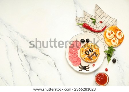 Plate with different tasty Halloween mini pizzas and sauce on light background