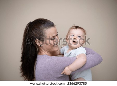 beautiful young mother with her baby son in front of brown background