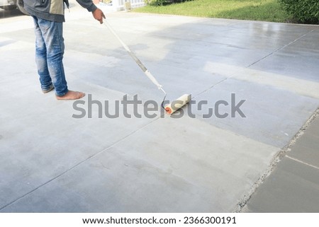 Worker and renovation work. To using roller painting mortar cement or finishing material for repair crack, skim coat or improvement surface of concrete pavement floor or slab for driveway or garage. Royalty-Free Stock Photo #2366300191