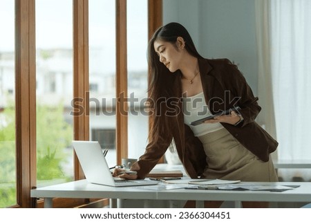 Thoughtful asian businesswoman checking financial reports at her office desk.
