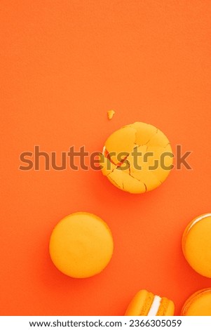 Orange color macarons flat lay on orange background.