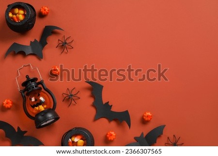 Composition with tasty candy corns, lantern and Halloween decor on brown background