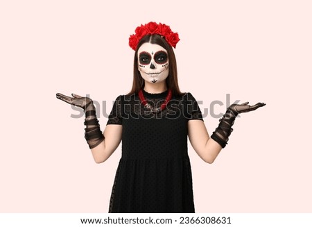 Young woman dressed for Halloween showing something on light background