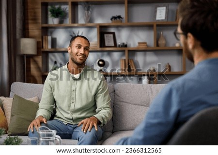 Visiting a psychologist A man sits on a couch and talks to a psychotherapist. He thanks the doctor and smiles, therapy helped him. Help of a psychologist. Royalty-Free Stock Photo #2366312565