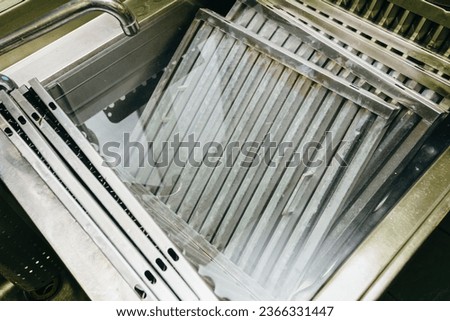 Heavy-duty sink containing multiple filters from industrial-grade hoods, immersed in a solution specifically designed for deep cleaning and degreasing Royalty-Free Stock Photo #2366331447