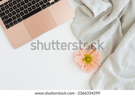 Laptop computer, crumpled cloth and poppy flower bud on white background with blank copy space. Flat lay, top view
