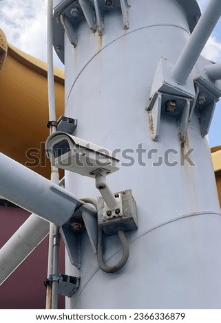 a photography of a camera mounted on a pole with a sky background.