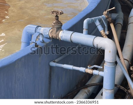 a photography of a blue boat with pipes and valves in the water, submarine style pipes and valves are connected to a blue boat.