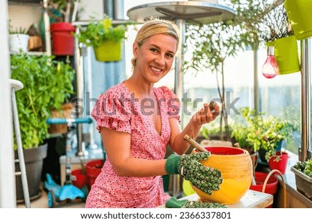 Happy woman planting avocado seed. She enjoys in gardening at her balcony.