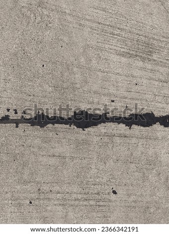 a photography of a person walking on a sidewalk with a skateboard, nail marks on the concrete surface of a road.