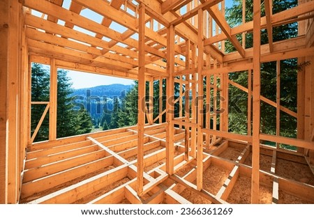 Wooden frame house under construction near forest. Beginning of new construction of cozy house on the edge of forest in mountains. Concept of modern ecological construction and modern architecture. Royalty-Free Stock Photo #2366361269