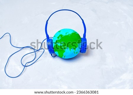 World globe adorned with blue headphones. Travel planning, destinations and cultures researching related concept.