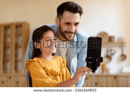 Online Fun With Dad. Happy Preteen Kid Daughter And Her Father Using Smartphone On Tripod, Shooting Video For Blog Or Making Photo Via Phone, Having Fun With Modern Gadget At Home. Selective Focus Royalty-Free Stock Photo #2366369855