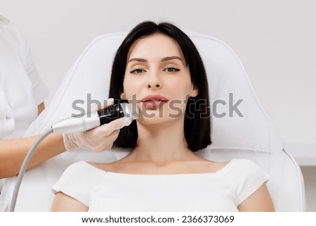 A young woman undergoes a radiofrequency facelift procedure. Advertising concept for facial skin care, anti-aging facial rejuvenation. Radio wave face lifting in a cosmetology clinic. Royalty-Free Stock Photo #2366373069