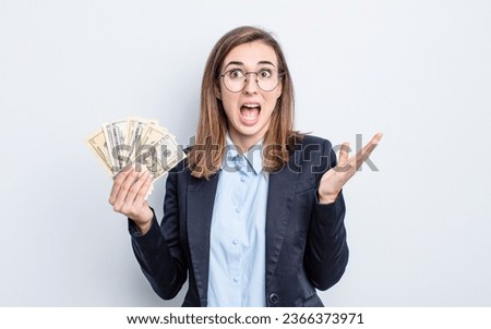 young pretty woman feeling happy and astonished at something unbelievable. dollar banknotes concept