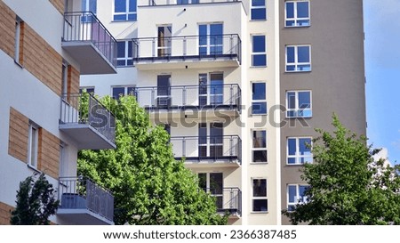 A modern residential building in the vicinity of trees. Ecology and green living in city, urban environment concept. Modern apartment building and green trees. Ecological housing architecture. 