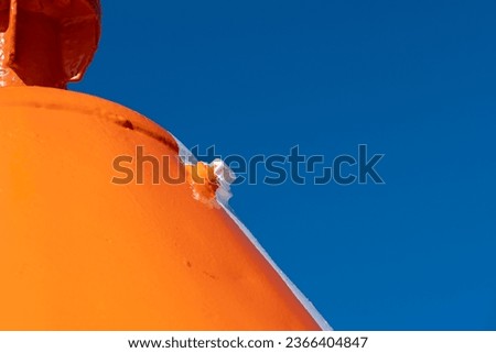 Robust, huge metal construction, painted bright orange with a white stripe. Clear, blue sky in the background. Copy space. Background for quotes. High quality photo