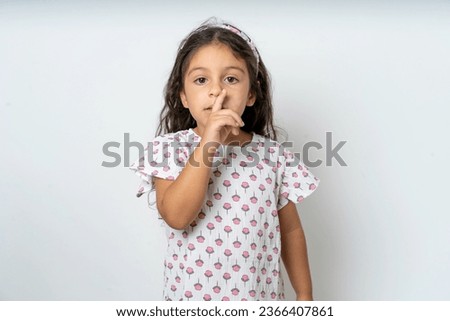 young beautiful kid girl makes silence gesture, keeps finger over lips. Silence and secret concept.