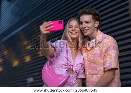 Gen Z couple in pink outfit taking selfie before going the cinema to watch movie.