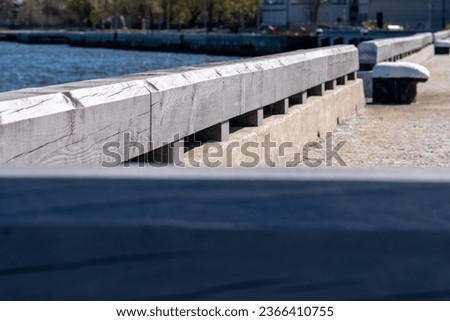 Harborside along the sea with a beautiful patterned light gray wooden fence in the port and light pavement. Blurred background. Copy space. Background for quotes. Royalty-Free Stock Photo #2366410755