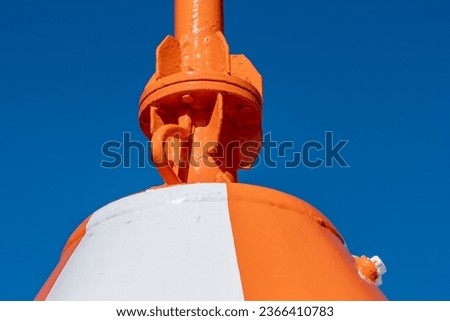Robust, huge metal construction, painted bright orange with a white stripe. Sea navigation buoys. Clear, blue sky in the background. Copy space. Background for quotes