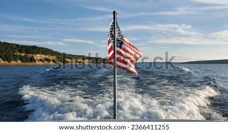 An American flag flys off the back of a boat in Michigan against the backdrop of pictured rocks.