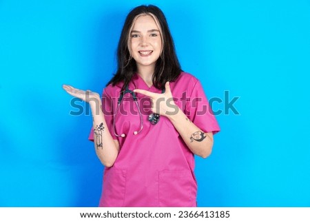 Positive young beautiful doctor woman promoter point index finger copy-space hold hand demonstrate offer ads promo or giving advice on something.