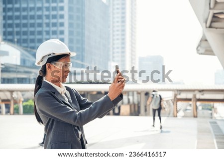 Civil women engineer wear safety white hard hat make a phone call in modern city. Young asian woman at construction site industry. Female engineer civil engineering with hard hat using smartphone.