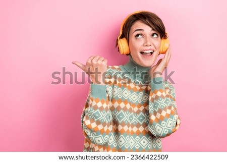Portrait of young girl bob hair winter season stylish outfit earphones point finger electronics store isolated on pink color background