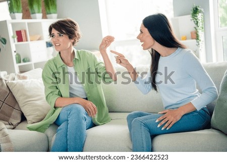 Portrait of two outraged unsatisfied lady sitting sofa fight ignore point finger count bright living room inside Royalty-Free Stock Photo #2366422523