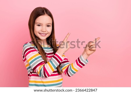 Photo of confident small promoter kid girl indicate fingers empty space recommend her entertainment hobby isolated on pink color background