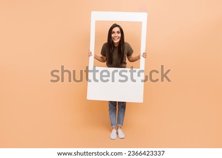 Full length photo of excited charming girl dressed khaki t-shirt tacking photo paper frame isolated beige color background