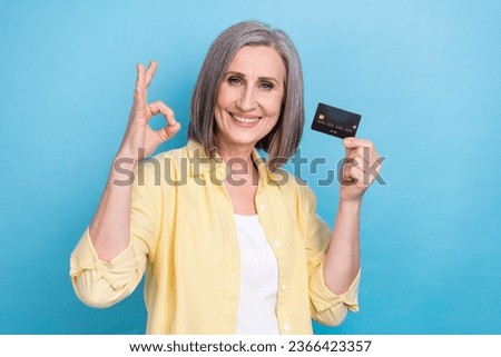 Photo of cute cheerful lady wear yellow shirt showing okey rising credit card isolated blue color background