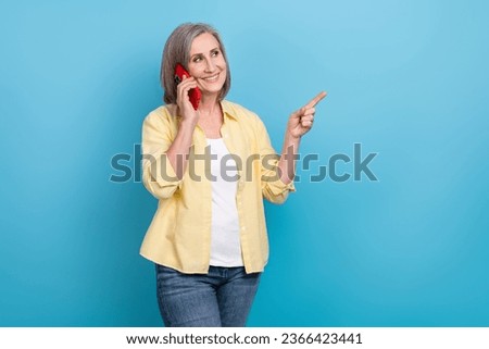 Photo of adorable dreamy lady wear yellow shirt speaking apple samsung iphone device finger empty space isolated blue color background