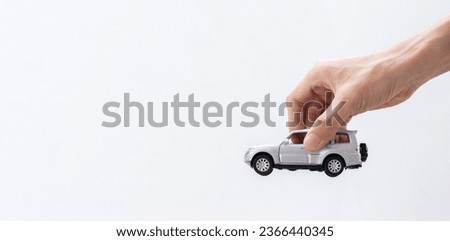Hand holding a toy car isolated on gradient background. After some edits. Royalty-Free Stock Photo #2366440345