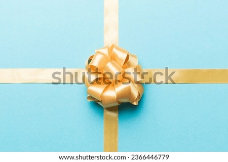 Top view of gold ribbon rolled and yellow bow isolated on colored background. Flat lay with copy space.