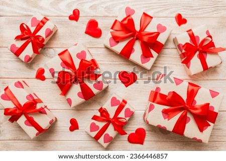Top view photo of valentine day decorations gift box with red ribbon bow on colored background. Holiday gift boxes with top view.