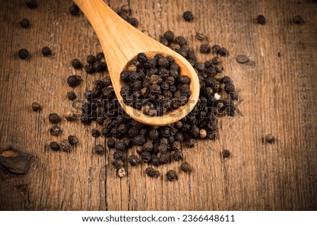 black pepper on wooden spoon and wood background