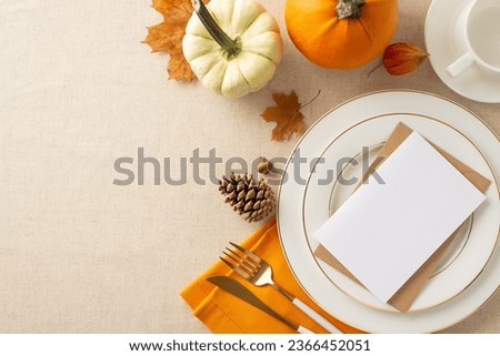 Create a warm Thanksgiving ambiance. Top-down view of plates settings, pumpkin accents, and autumnal touches on a soothing beige tablecloth. Envelope with empty paper sheet - perfect for text or ads