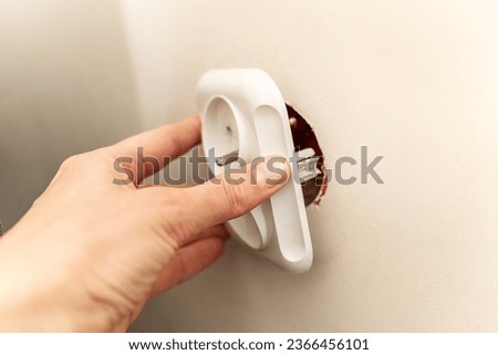 White broken electrical socket fell out of the wall. The socket is torn from the wall. A violation of electric safety, risk of electric shock	 Royalty-Free Stock Photo #2366456101