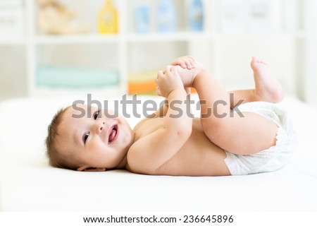happy baby lying on white sheet and holding his legs Royalty-Free Stock Photo #236645896