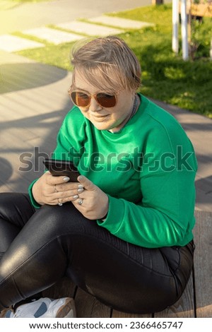 Plus size woman with smartphone. Natural. Woman freelancer in park. Vertical