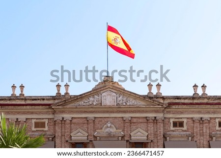 flag of spain on official building raised on a flagpole in the breeze on a sunny day. horizontal photograph.