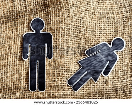 The concept of abuse, death, separation, divorce in couple. Bad addiction to alcohol or drugs. Paper black figurines of a man and a woman and one of them dominates. Abstract background, texture