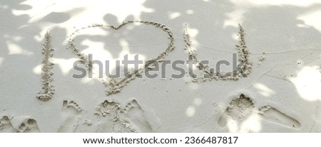 The image shows the phrase "I love you" written in the sand. It is a romantic message expressed through a visual gesture. The words are written in large, capital letters, creating a bold and heartfelt